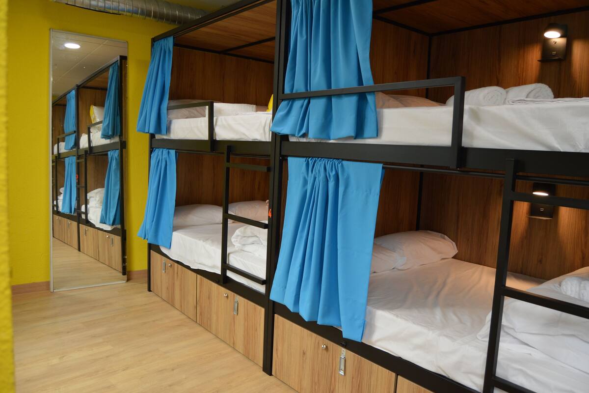 A dormitory room with bunk beds, wooden walls, and a mirror.