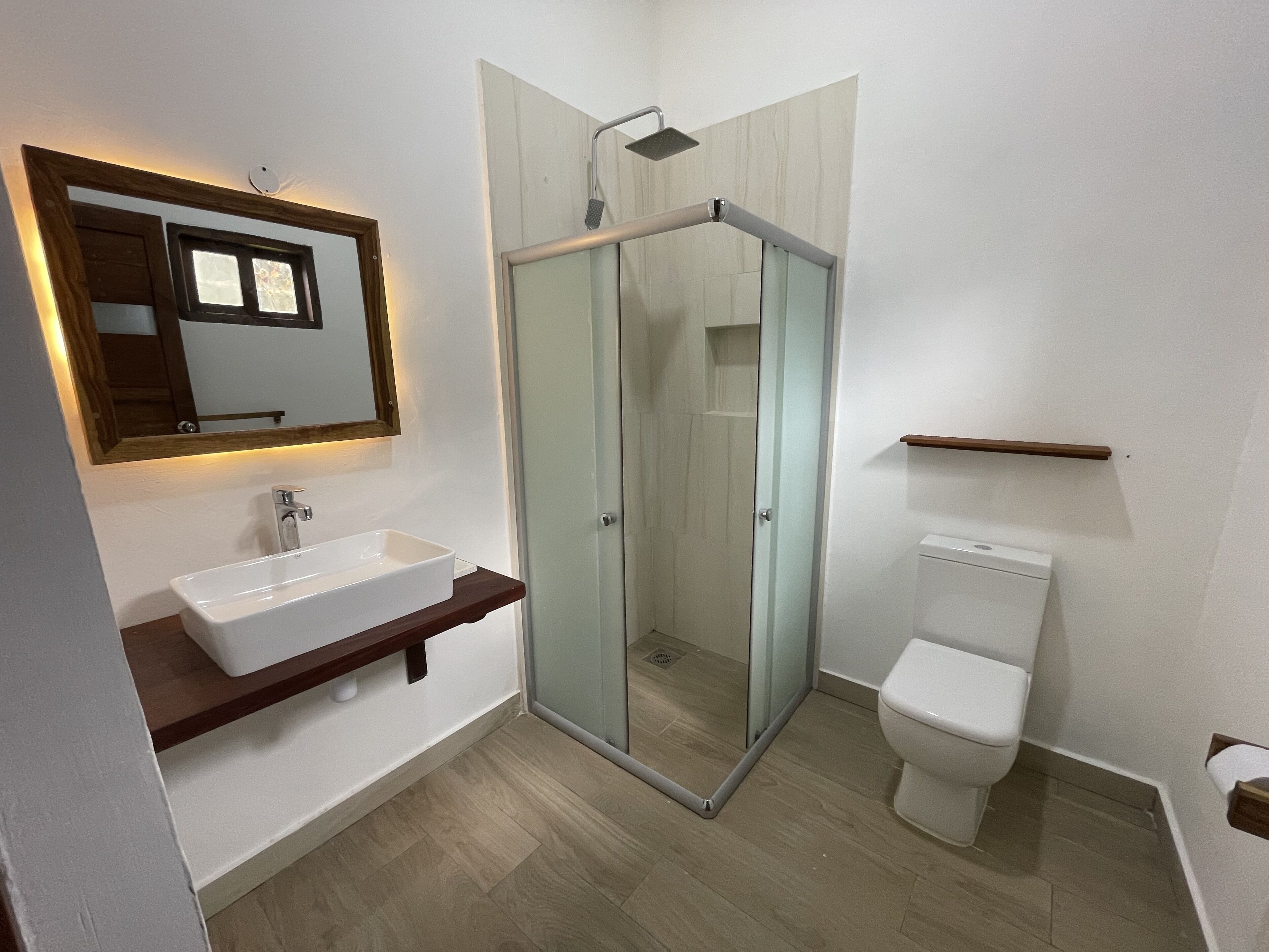 Une salle de bain moderne avec une douche à parois de verre, un lavabo blanc et des toilettes.