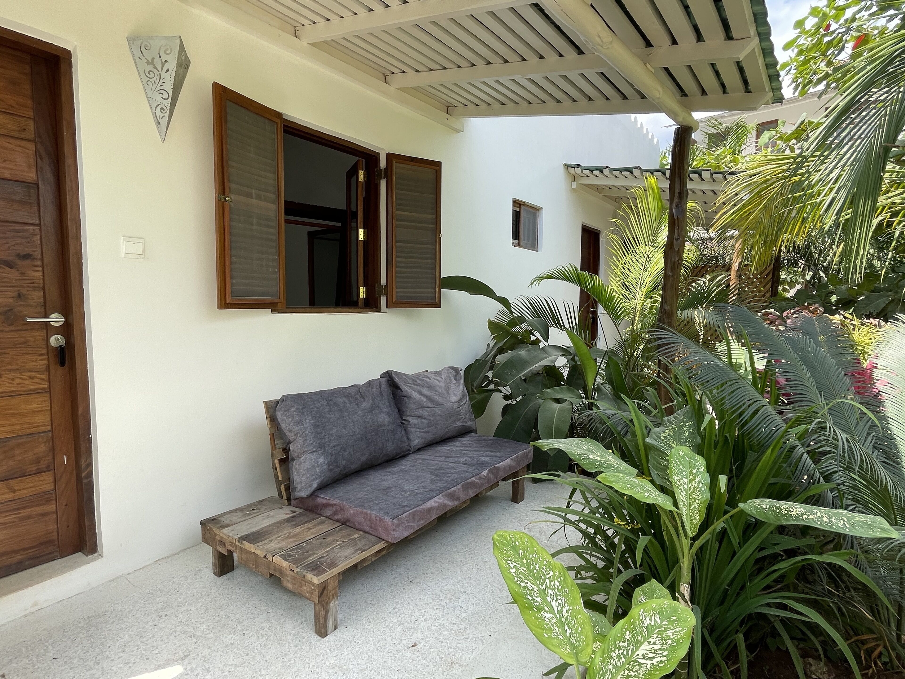 A room with a wooden bench, a grey sofa, and a wooden door.