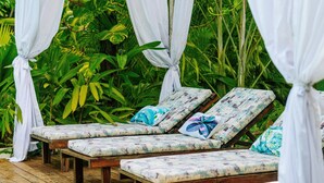 A wooden deck with four lounge chairs, each with a floral cushion. - Gaia Villas (Nungwi)