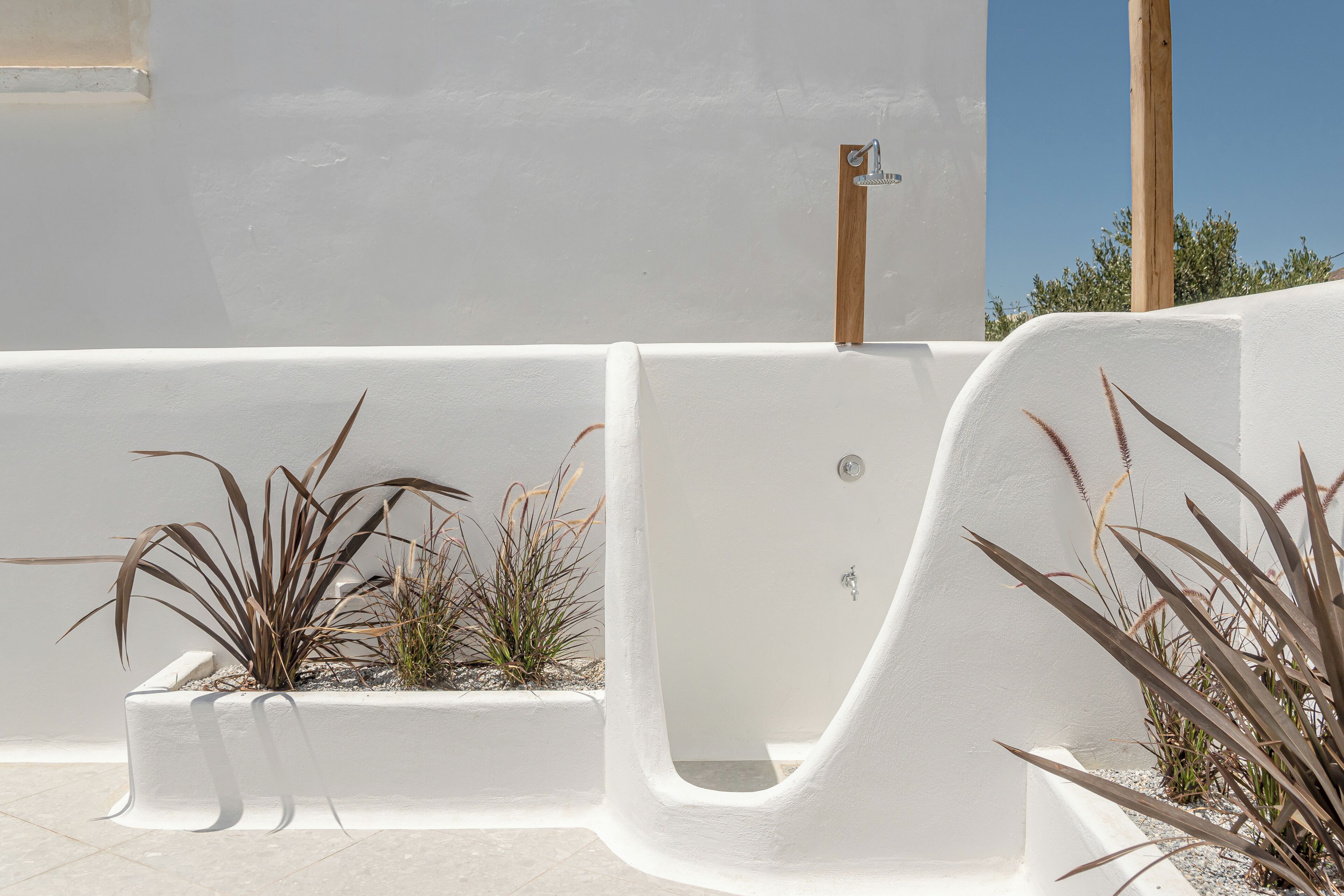 A white outdoor area with a built-in planter and a water feature.