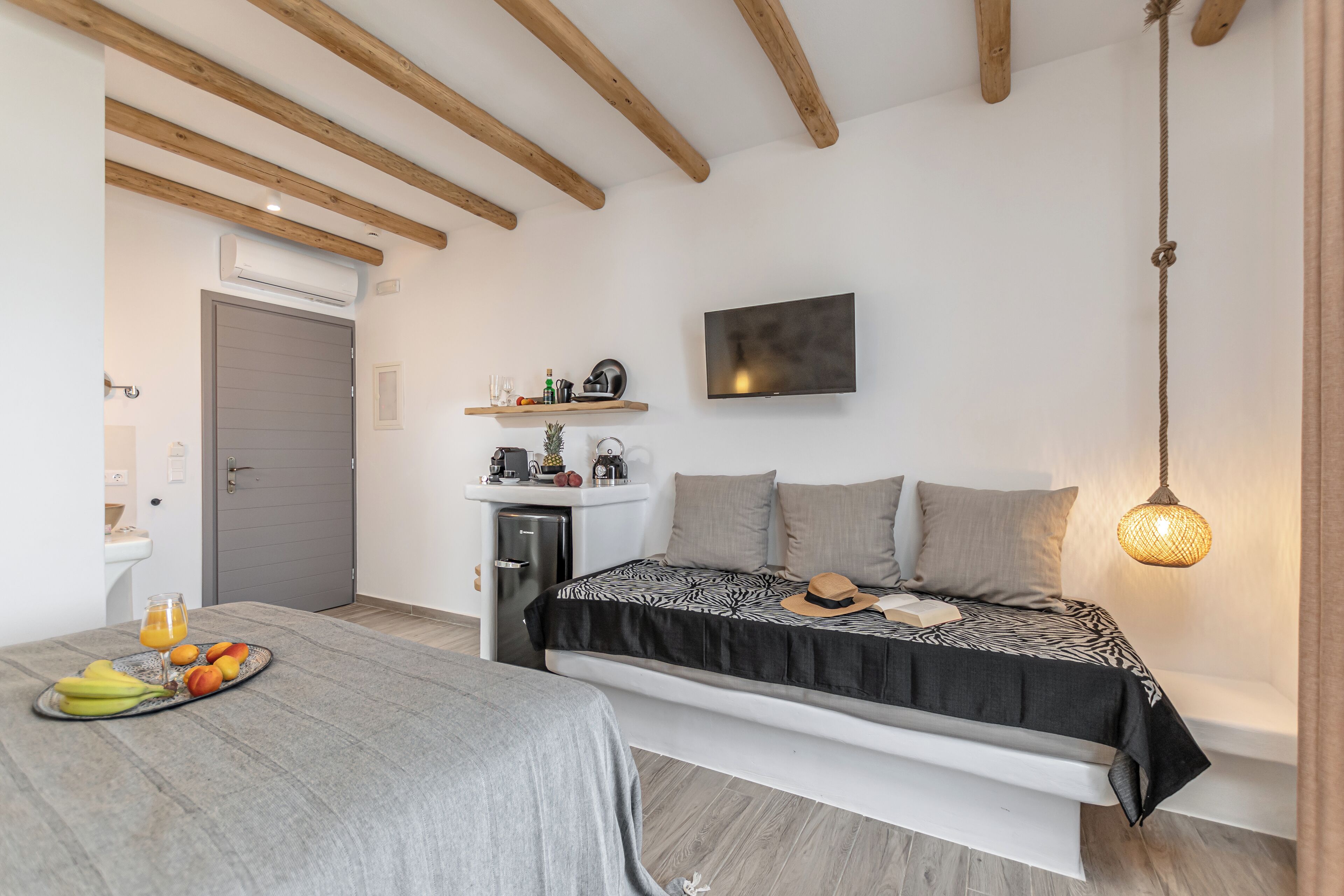 Een moderne slaapkamer met een bed, nachtkastje en een kleine kitchenette.