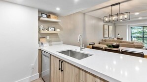 A modern kitchen with white countertops, a double sink, and wooden cabinets.