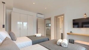 Ein modernes Hotelzimmer mit zwei Betten, einem Fernseher, einem Spiegel und einem Kleiderschrank.