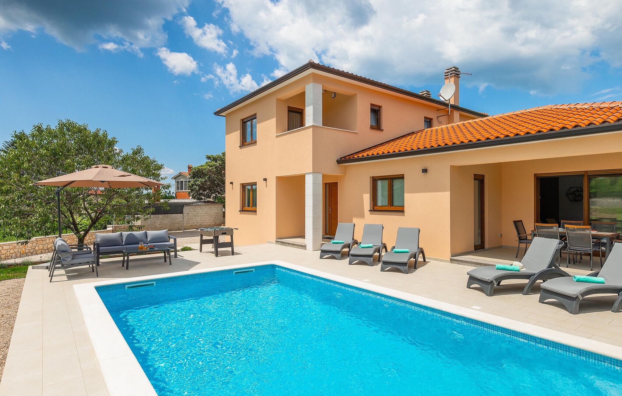 Une maison à deux étages avec une piscine, un espace salon extérieur et une antenne parabolique.
