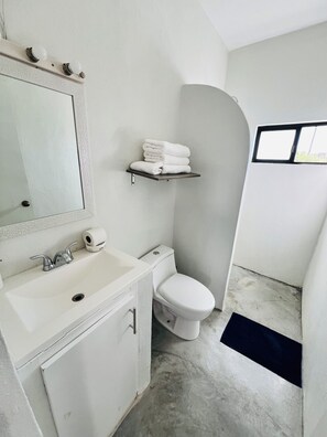 Une salle de bain avec un lavabo blanc, un miroir, des toilettes et un porte-serviettes.
