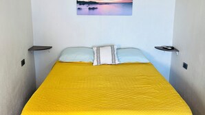 Ein Zimmer mit einem Bett, einem Gemälde und einer Klimaanlage.