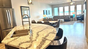 Eine moderne Küche mit einer Granit Arbeitsplatte, Edelstahlgeräten und einem Essbereich mit einer Couch und Stühlen.