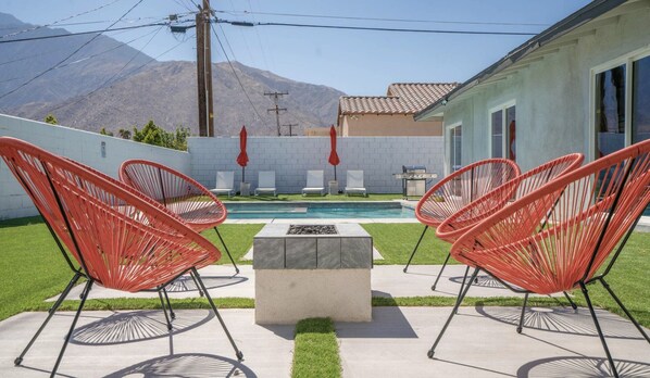 A poolside area with red chairs, a concrete table, and a view of mountains. - Absolutely beautiful and stylish Palm Springs home!!! Relax and have fun!! (Palm Springs)