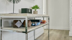 Een moderne, minimalistische kamer met een tafel met glazen blad, een kamerplant en netjes opgeruimde dozen en boeken.