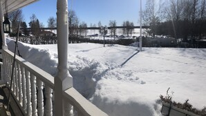 A snow-covered outdoor area with a railing, a metal pole, and a clear sky. - Headlineee (Norrbottens län)