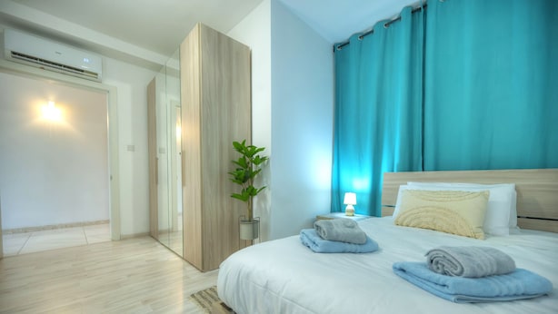 Una habitación de hotel moderna con una cama grande, una mesita de noche, una lámpara y una planta en maceta.