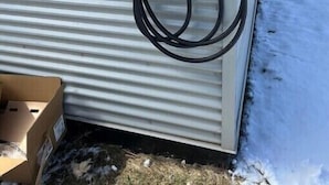 An outdoor electrical box with a Leviton brand device and a cable connected to it, mounted on a corrugated metal wall.