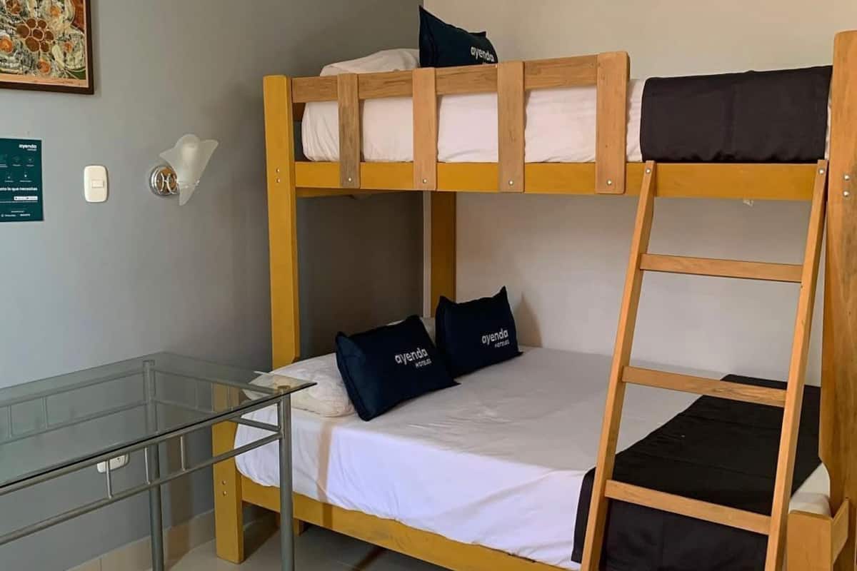 Una cama litera con escalera, un escritorio con silla y un panel de vidrio.