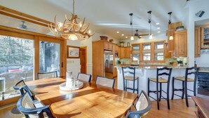 Une cuisine spacieuse avec des meubles de rangement en bois, un grand îlot central doté de tabourets et un lustre.