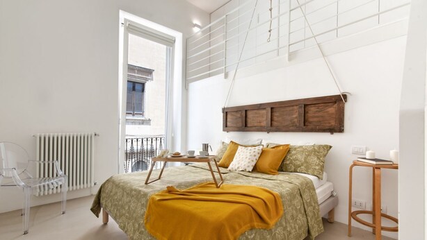 Une chambre à coucher avec un lit, une table de chevet et une chaise. Il y a une fenêtre donnant sur l’extérieur.