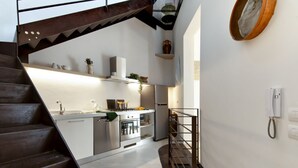 Une cuisine moderne dotée d’appareils électroménagers en acier inoxydable, d’un escalier en bois et d’un téléphone fixé au mur.