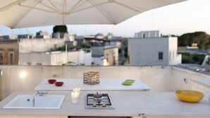 Un espace extérieur aménagé pour les repas, avec une table, des chaises et un grand parasol.
