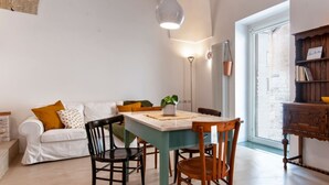 Un coin repas accueillant avec une table et des chaises, un meuble en bois agrémenté d’objets décoratifs et un canapé blanc avec des coussins.