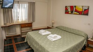 A hotel room with a bed, a desk, a chair, a television, and a painting on the wall. - Aspen Ski Hotel (San Carlos de Bariloche)