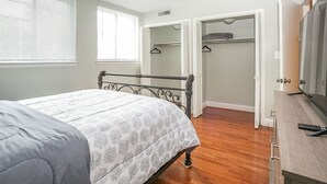 Ein Schlafzimmer mit Bett, Kleiderschrank, Schreibtisch und Fernseher.