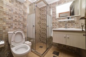 A bathroom with a shower enclosure, toilet, sink, and a mirror above the sink. - Batroun Boutique suites (Batroun)