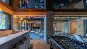 Espai interior modern amb taula de futbolí, zona de seients i barra.