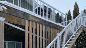 A wooden staircase leading to a building with a metal railing, surrounded by snow. - Spacious 2 Bdm close to Airport

 (Regina)