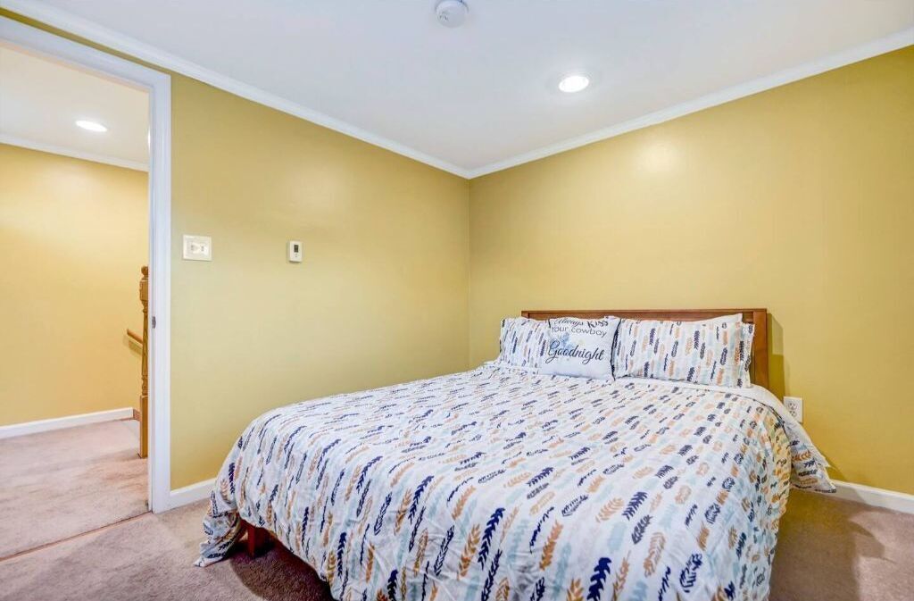 Ein Schlafzimmer mit einem Bett, einer T ür und einem Lichtschalter an der Wand.