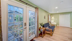 A room with a sliding glass door leading to a garden, a wooden bench, a small table with a plant, and a sofa with cushions. - Newly renovated, game room, skiing, sauna, water parks, golf, suites  (Cresco)