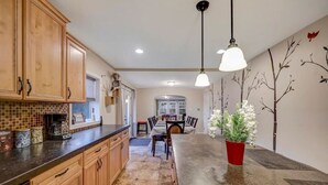 A kitchen with wooden cabinets, a tiled backsplash, a central island, and a dining area with a table and chairs. - Newly renovated, game room, skiing, sauna, water parks, golf, suites  (Cresco)