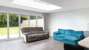A modern living room with a grey sofa, a blue sofa, and a dining table. - Field View 5-bed House - Free Parking (Burton on Trent)