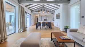 A spacious living area with a high ceiling, a dining area, and a kitchen.