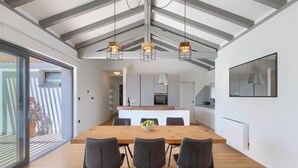 A modern kitchen with a central island, a dining area with a wooden table and four chairs, and a large window providing natural light.