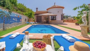 A poolside area with lounge chairs, a mosaic wall, a small building, and a statue. - Villa Almijara Cómpeta by Ruralidays (Málaga)