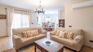 A living room with two beige sofas, a wooden coffee table, and a chandelier. - Villa Almijara Cómpeta by Ruralidays (Málaga)