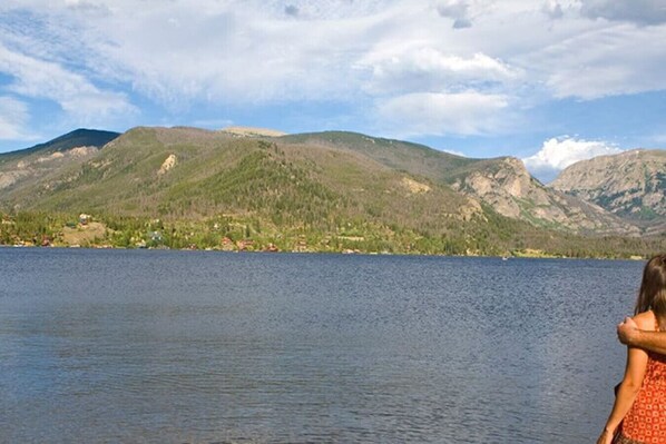A lake with mountains in the background and a person in the foreground.
