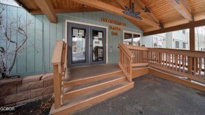 A building with a wooden exterior, a staircase leading to a door labeled "WASHER DRYER," and a sign indicating a "SPA" on the right. - Riverside Ground-Level Condo in Funky Fraser. (Fraser)