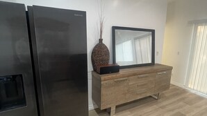 Eine moderne Küche mit einem schwarzen Kühlschrank, einem Holzkabinett und einer Vase mit Zweigen.