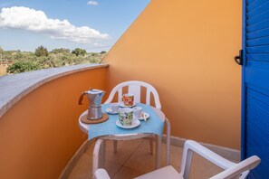 Un balcó amb una taula preparada per a dues persones, una cafetera i una tassa.