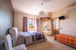 A bedroom with a bed, a sofa, a ladder, a TV, and a window with curtains.