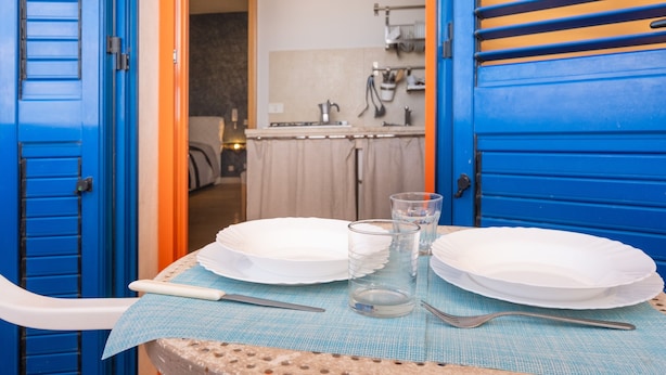 A dining table with plates, glasses, and cutlery, set against a blue door and wall.