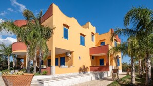 A multi-story building with a yellow facade, blue shutters, and a stone-paved entrance.