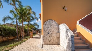 A paved pathway leading to a stone entrance with a staircase.