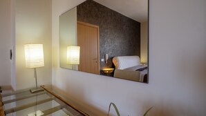 A hotel room with a large mirror, a bed, a bedside table with a lamp, and a glass railing in the foreground. - Apartment "Terra E Colori Bilo 1" with Wi-Fi & Air Conditioning (Gallipoli)