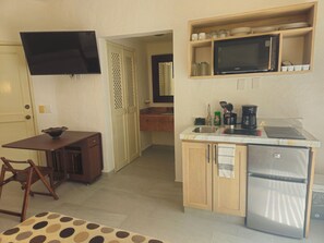 A compact kitchen with a refrigerator, microwave, sink, and a dining area with a table and chairs.