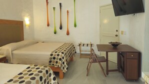 Hotellihuone, jossa on kaksi sänkyä, työpöytä, televisio ja seinään kiinnitetty valaisin.
