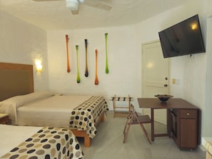 Une chambre d’hôtel avec deux lits, un bureau, une télévision et un luminaire fixé au mur.