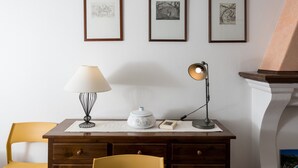 Un bureau avec une lampe, un livre et un tableau encadré accroché au mur.