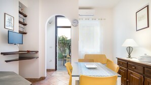Une cuisine compacte avec un coin repas, un téléviseur fixé au mur et une fenêtre avec des rideaux.